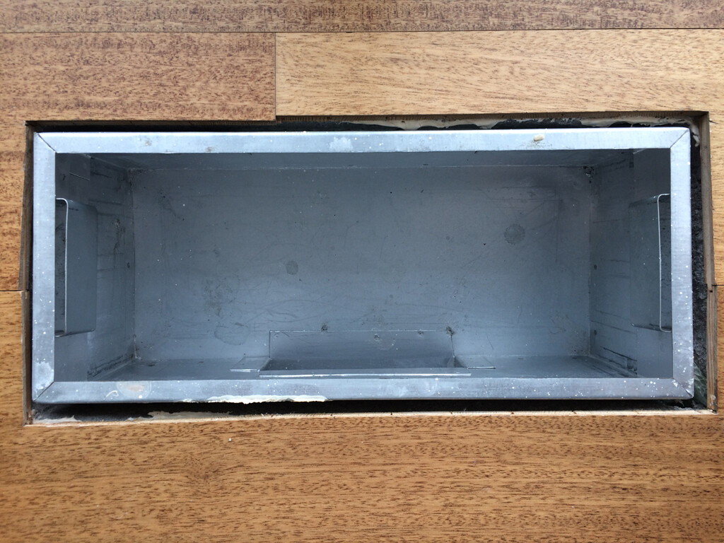 Empty rectangular metal box in wooden frame, interior gray.