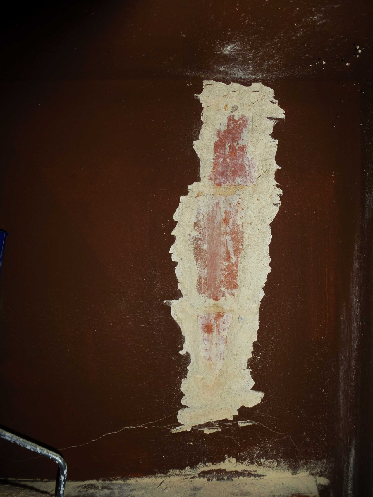 Cracked brown wall with damaged plaster and exposed brickwork