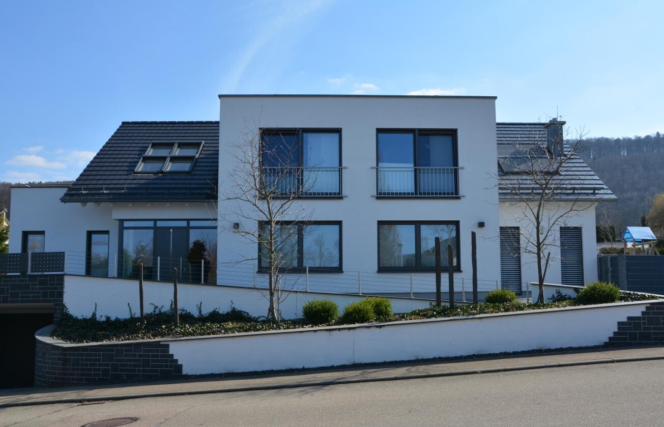 Modern white villa with two floors, large windows, balconies and front garden.