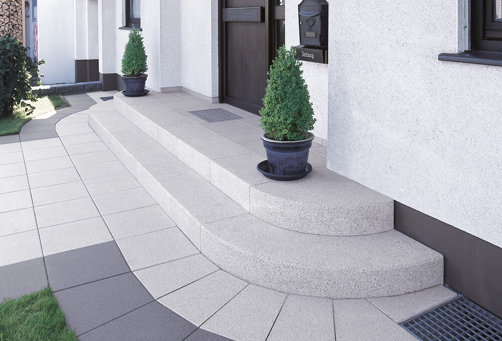 Bright house entrance, three-step staircase, two green conifers in blue pots.