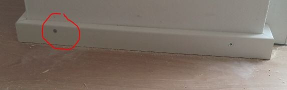Small hole in the white baseboard right at the floor inside a room