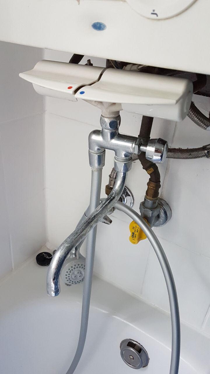 Unter der Spüle sind Sanitärrohre, Ventile und Armaturen sichtbar