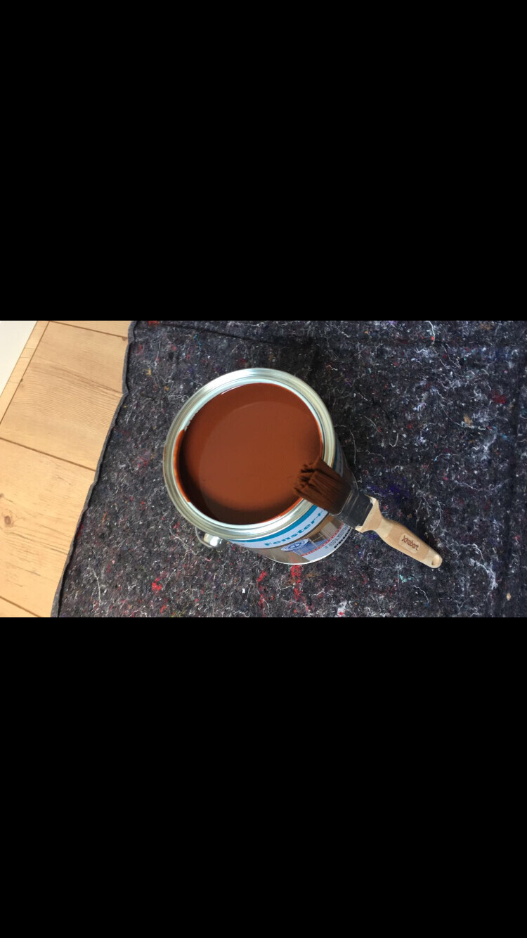 Brown paint can with brush on a workspace during interior construction.