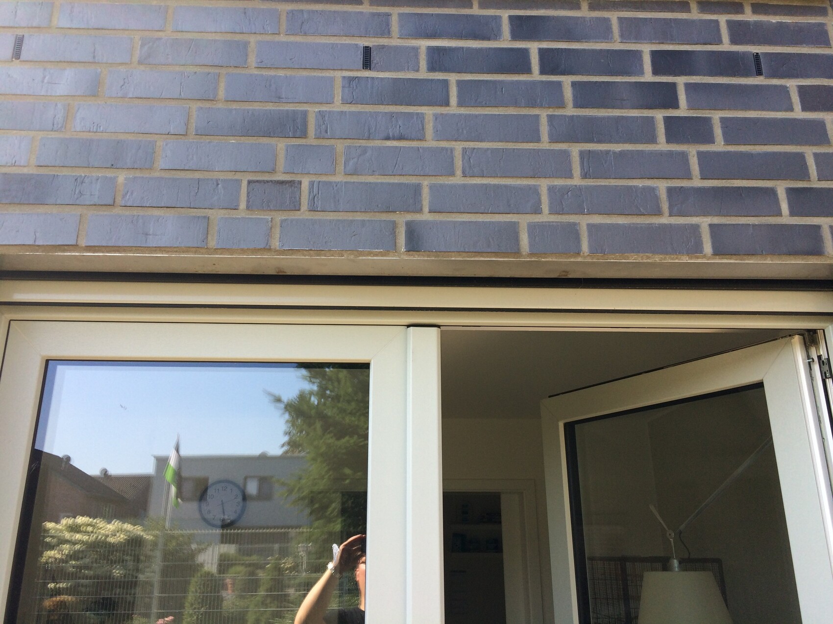Exterior view of a front door with glass window in front of gray-blue brick wall