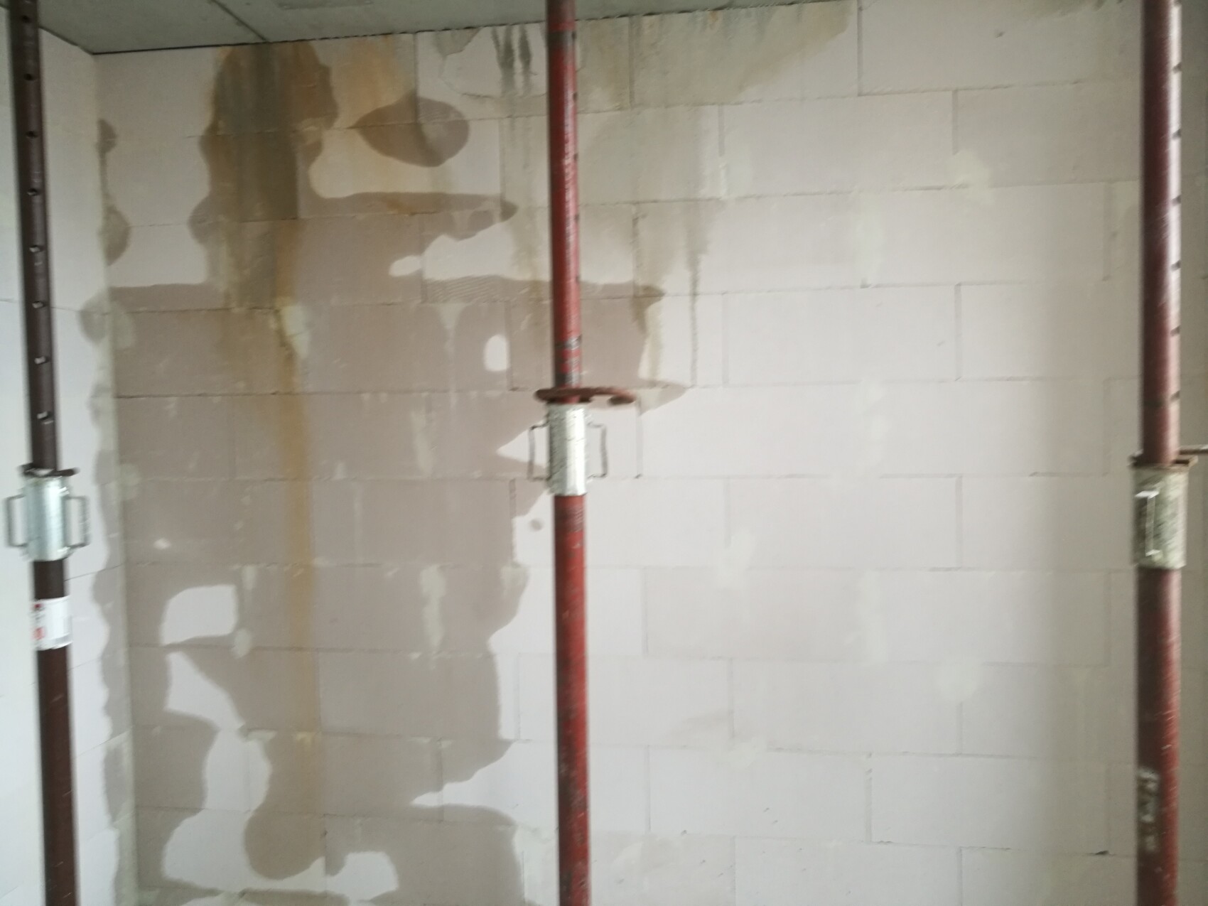 Interior wall made of blocks with red pipe system and clamps at construction site