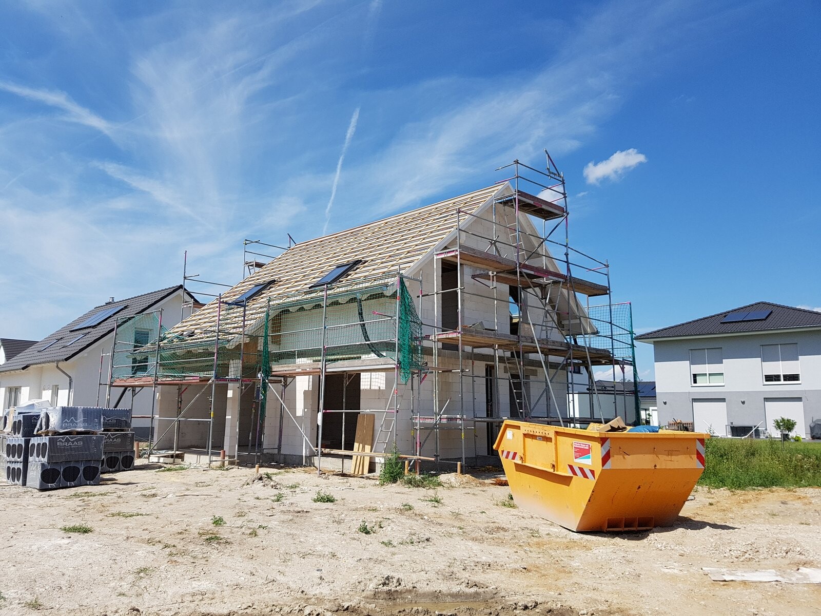 Rohbau eines Einfamilienhauses mit Geruesten auf einer Baustelle
