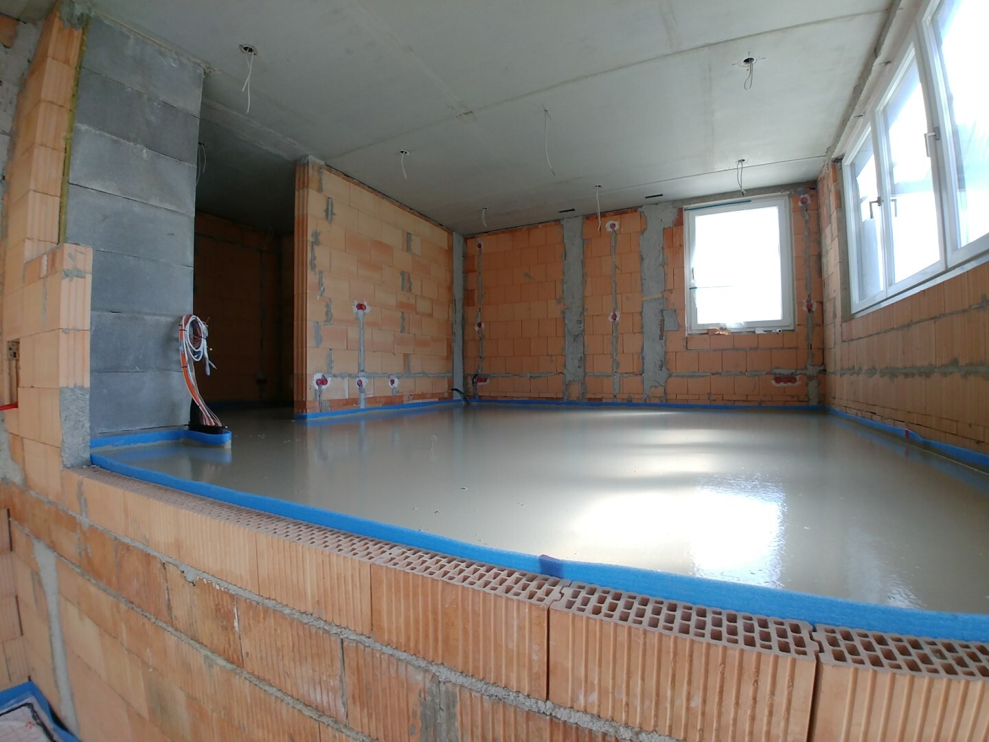 Shell of an indoor pool with brick walls, smooth floor, windows and installations.