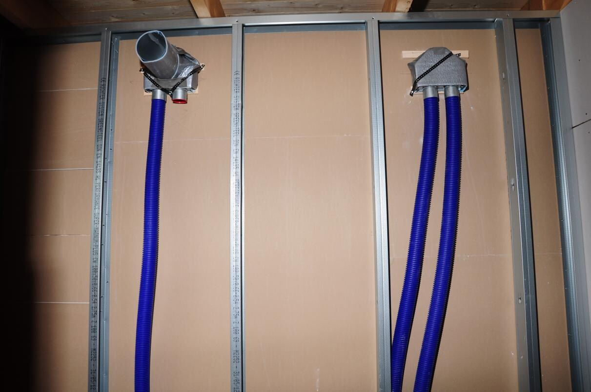 Unfinished interior wall with metal studs and blue flexible pipes for building services in shell construction