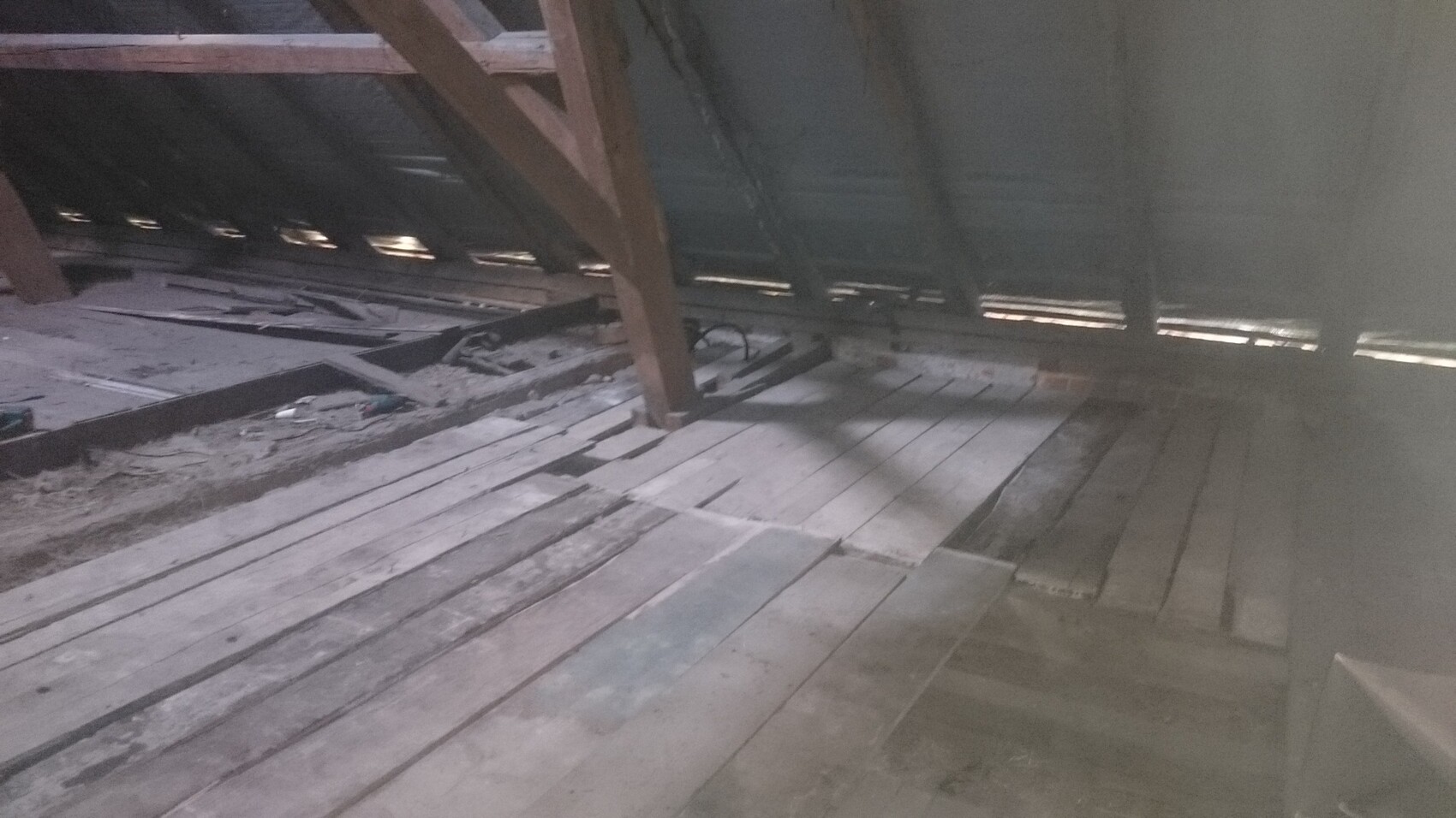 Dachboden mit staubigem Holzboden, Holzbalken und verstreutem Bauholzschrott.
