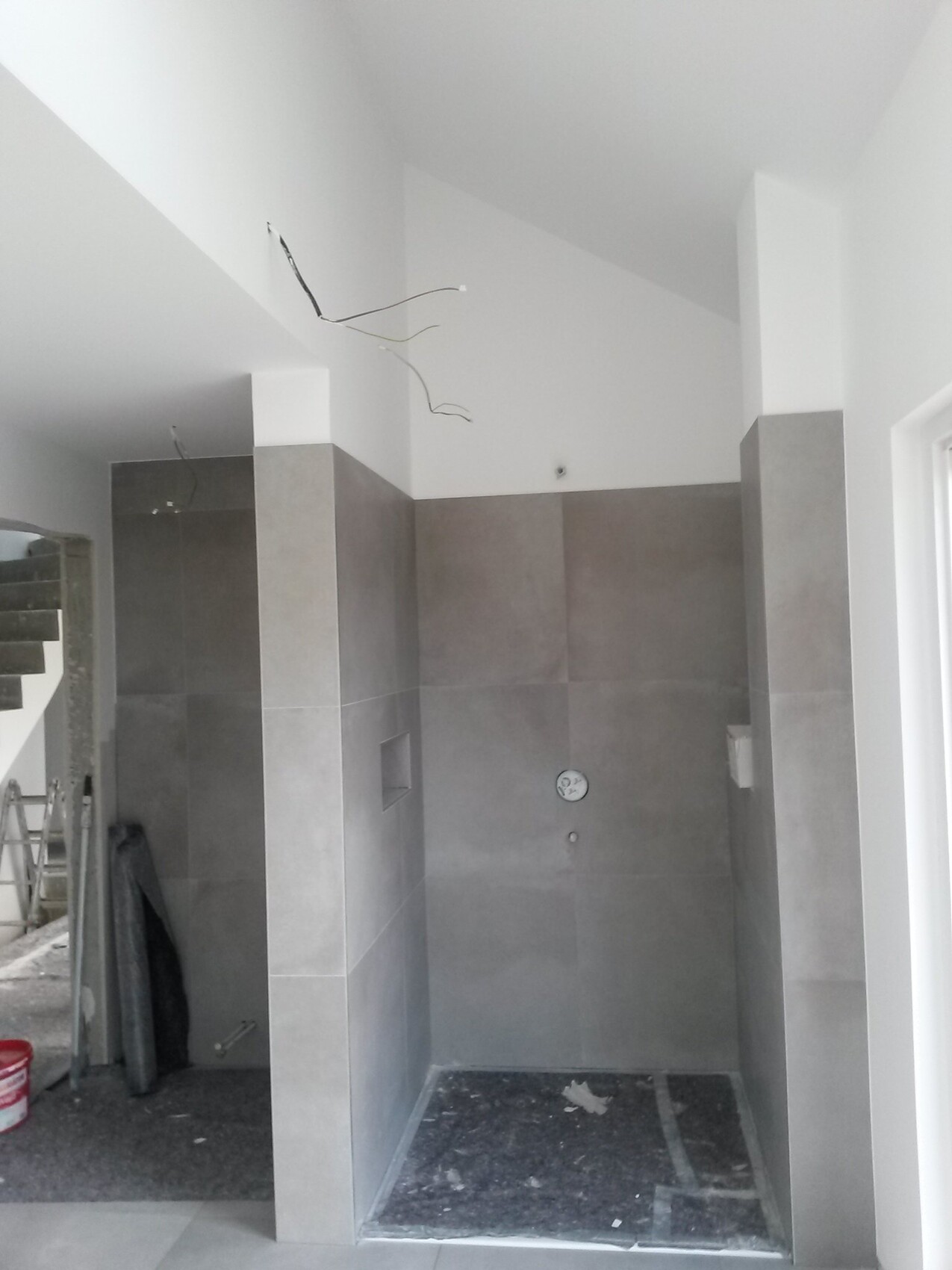 Construction phase: gray tiles in the shower, loose cables hanging from the ceiling.