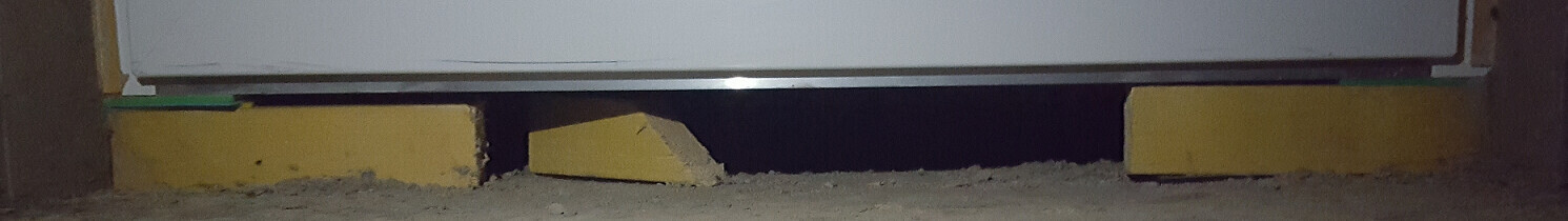 Blick unter ein Bauteil auf einer Baustelle mit gelben Keilen als Unterbau