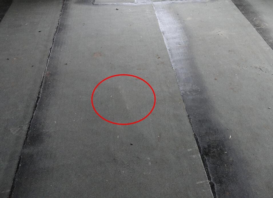 Concrete floor with red circular marking around a small damage or irregularity