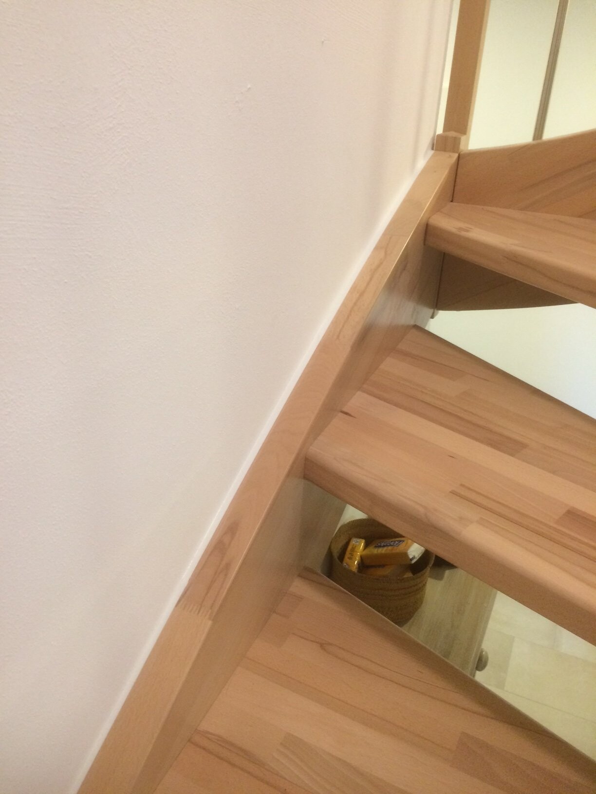 Light wooden staircase with open steps; below a basket with snack bars.