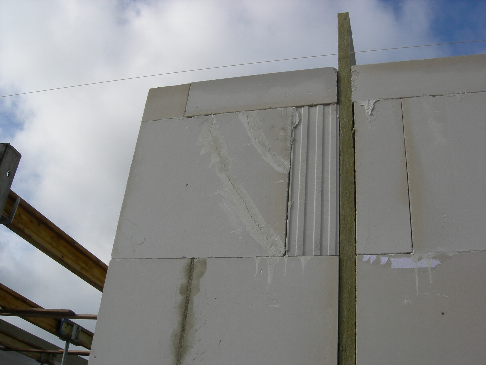 Partially finished concrete block wall on a construction site with wooden beams against the sky