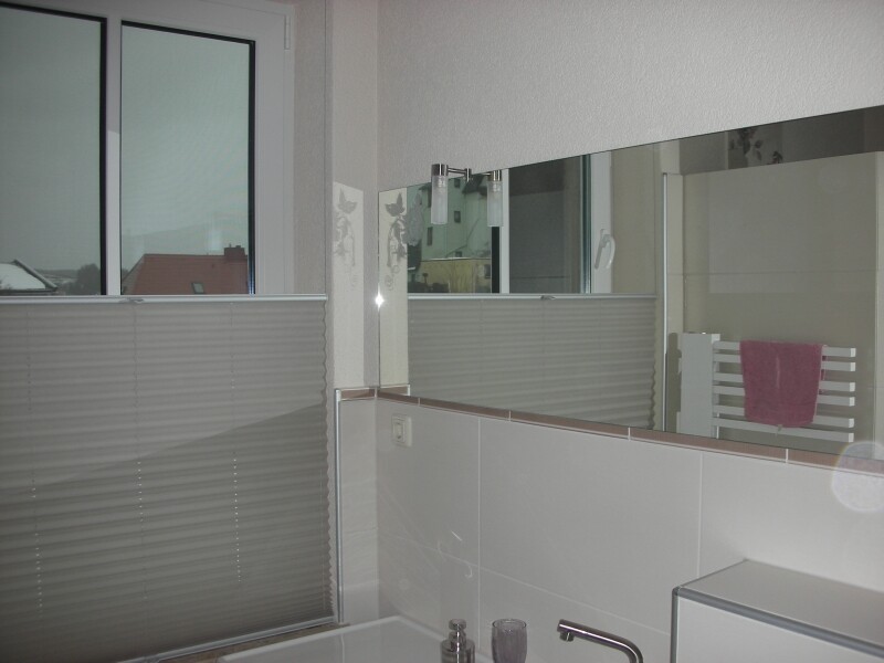 Bathroom with window, blinds, mirror, sink, and pink towel on the radiator.