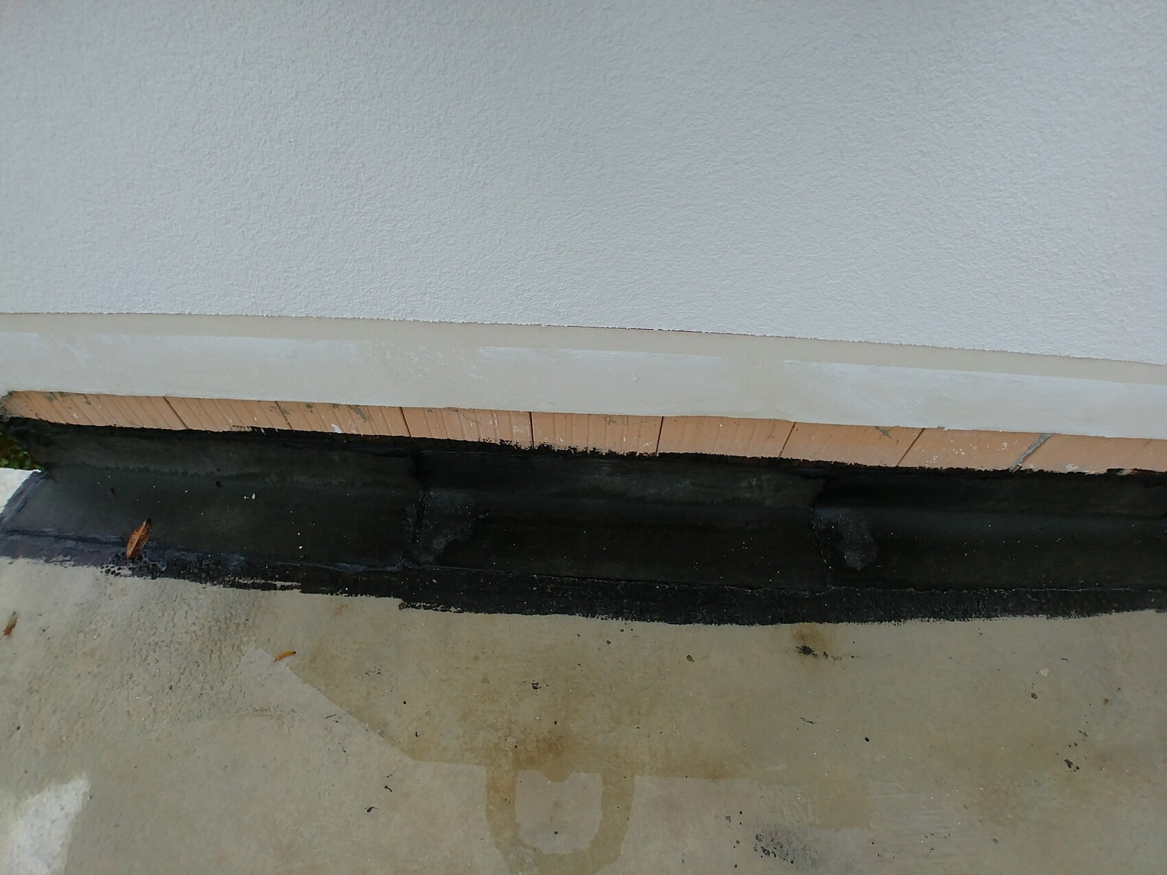 Bottom edge of an external wall with black waterproofing on the foundation