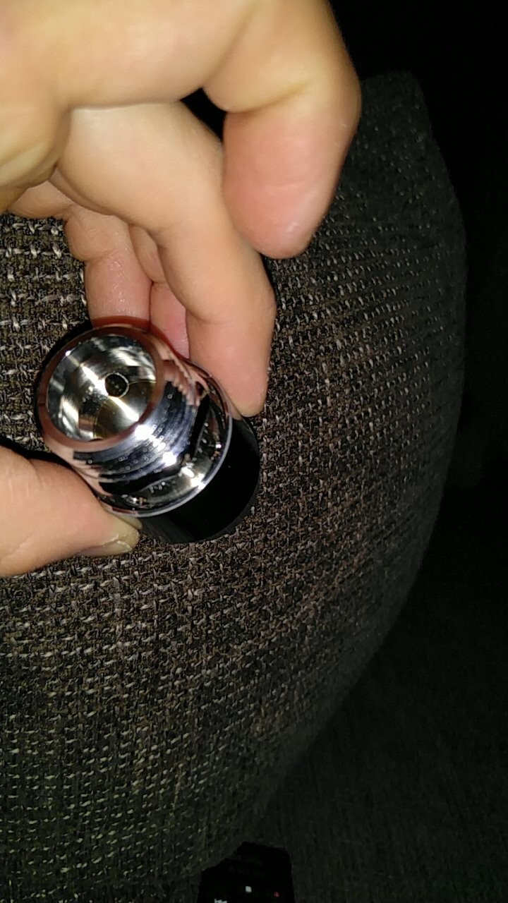 Person holding a shiny lock cylinder in hand against dark fabric