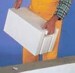 Small white 3D house model held in hand against blue background.