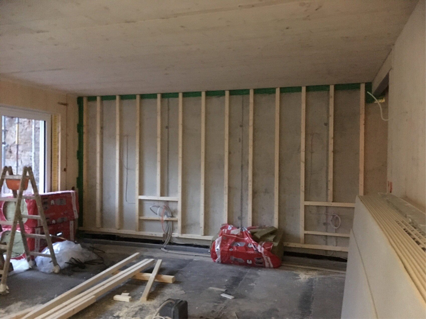 Baustelle im Innenraum mit Holzständerwänden, Leiter und Baumaterialien