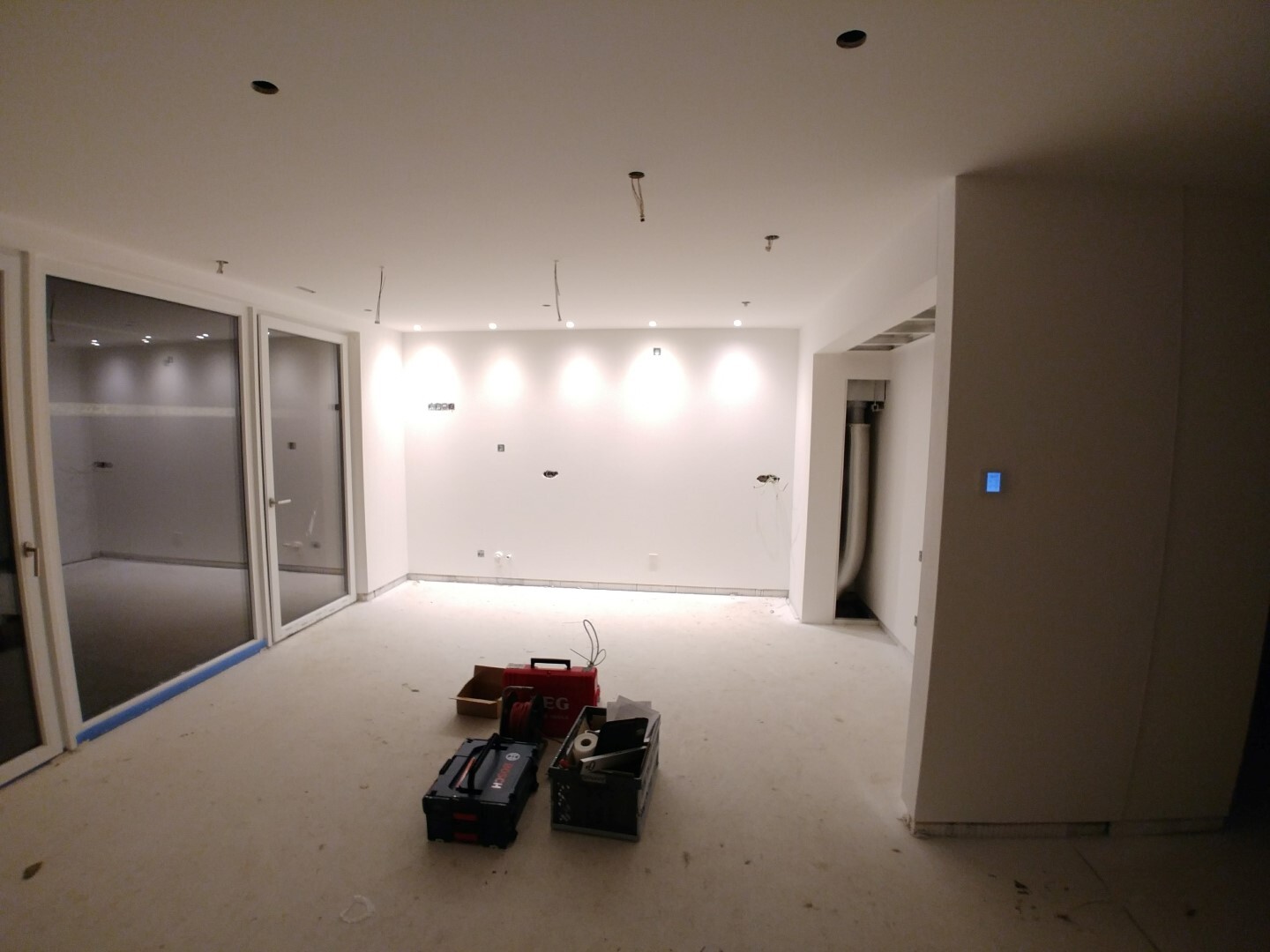 Heller unfertiger Wohnraum im Innenausbau mit Glastüren und sichtbaren Elektroinstallationen