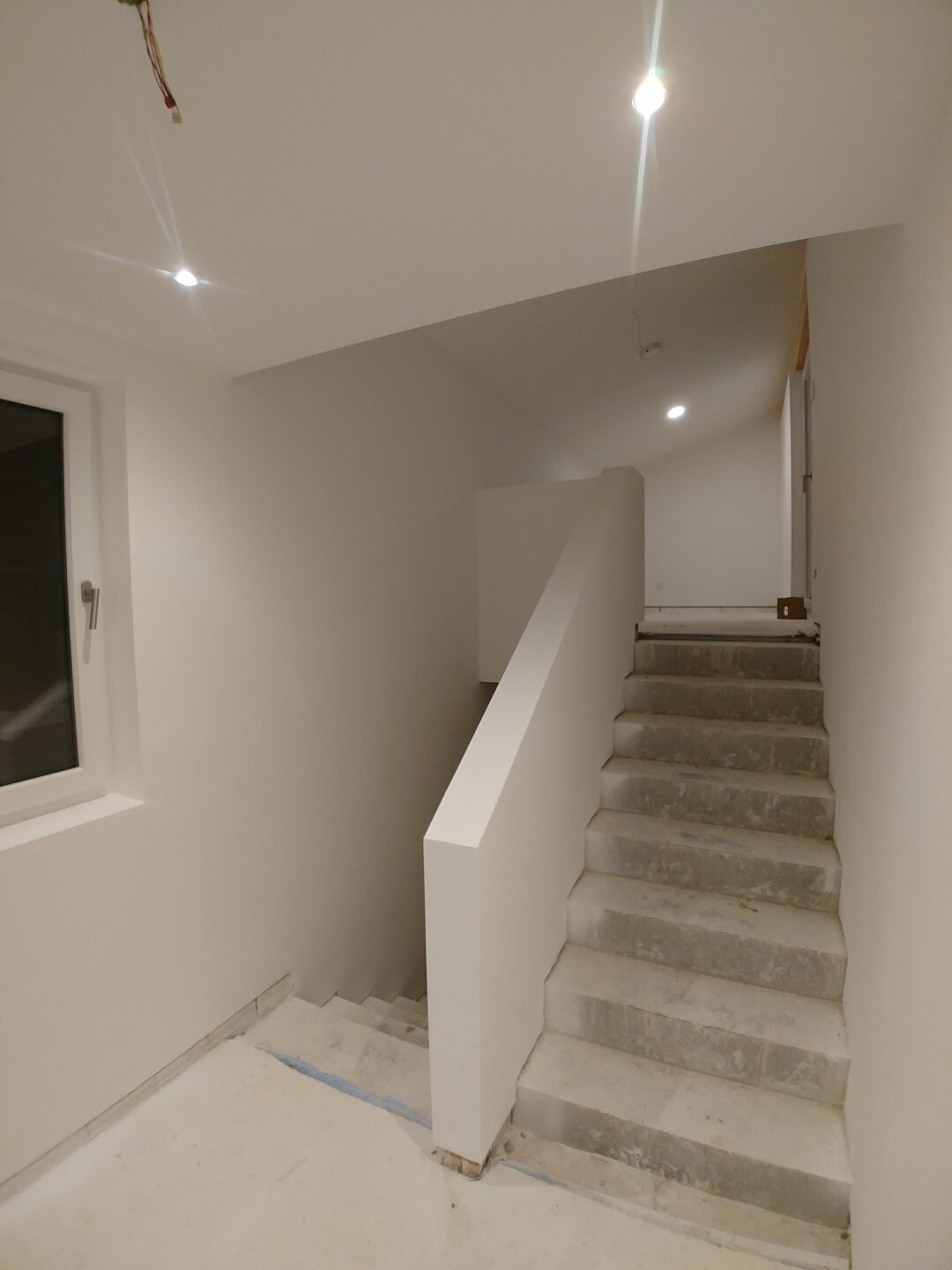 Heller Innenbereich mit Treppe, Geländer und weißen Wänden in einem Neubau