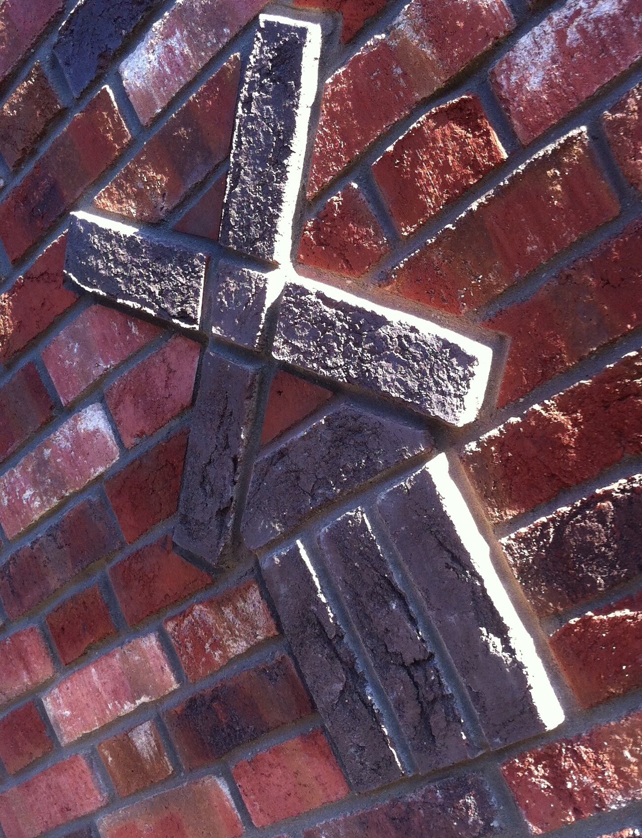 Close-up of red brick wall with light cross of bricks