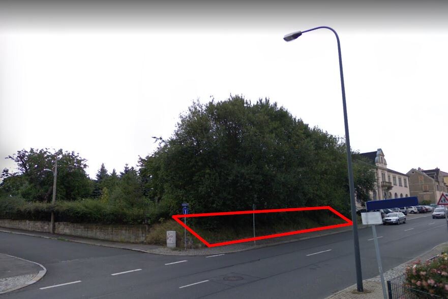 Road with red border marking property boundary next to trees and buildings