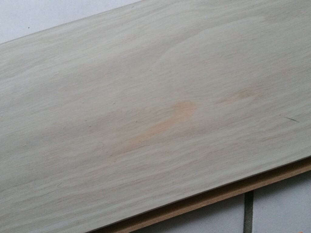 Light wooden slat with orange stain on tiled floor