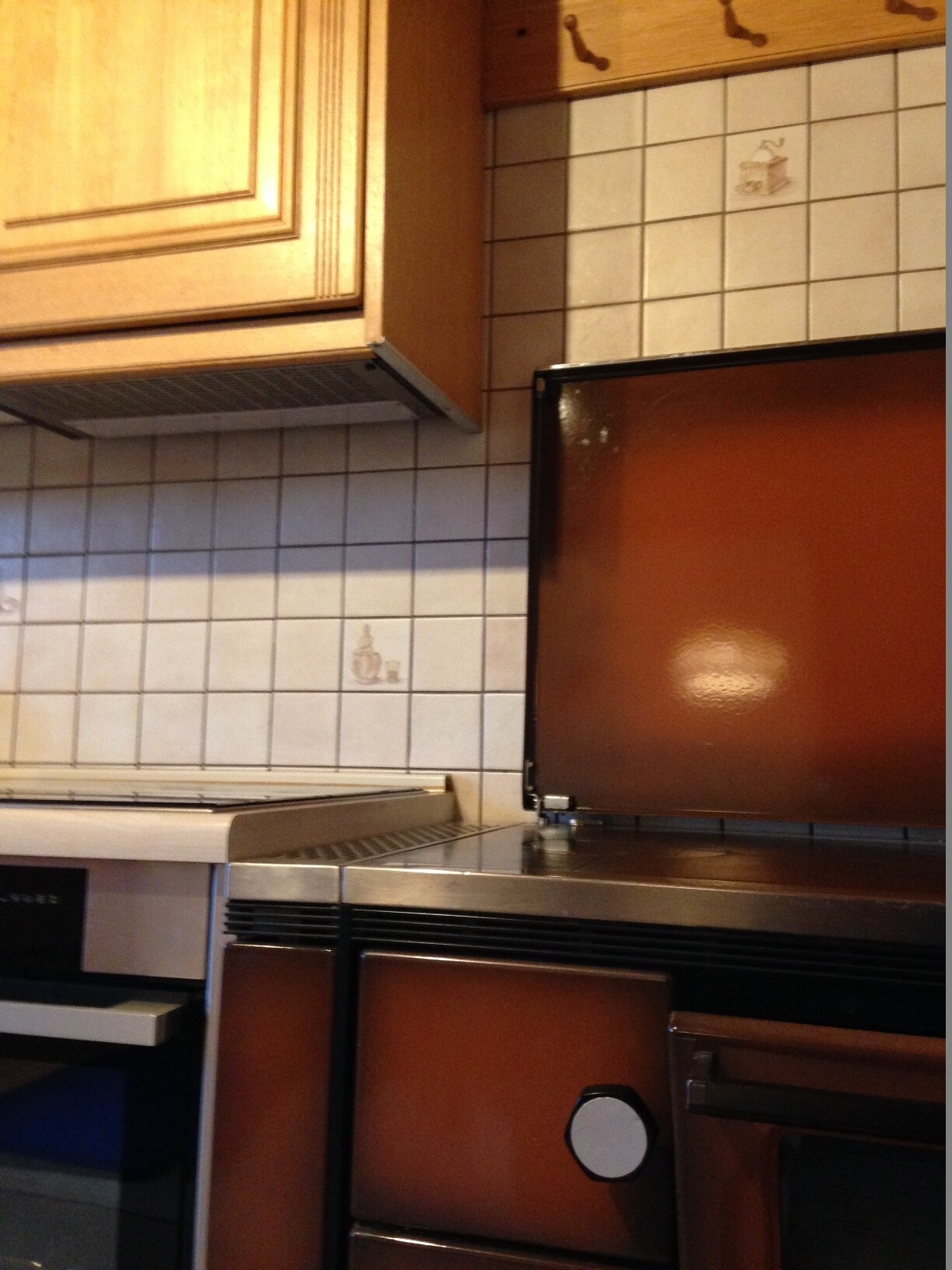 Retro kitchen with brown stove front, wooden cabinets, and light tiles in the background
