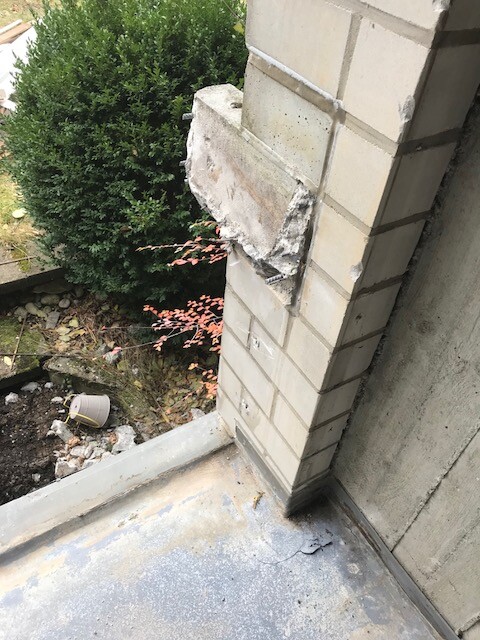 Außenwand-Eckbereich mit beschädigter Bruchstelle aus Stein und Zement an einer Fassade