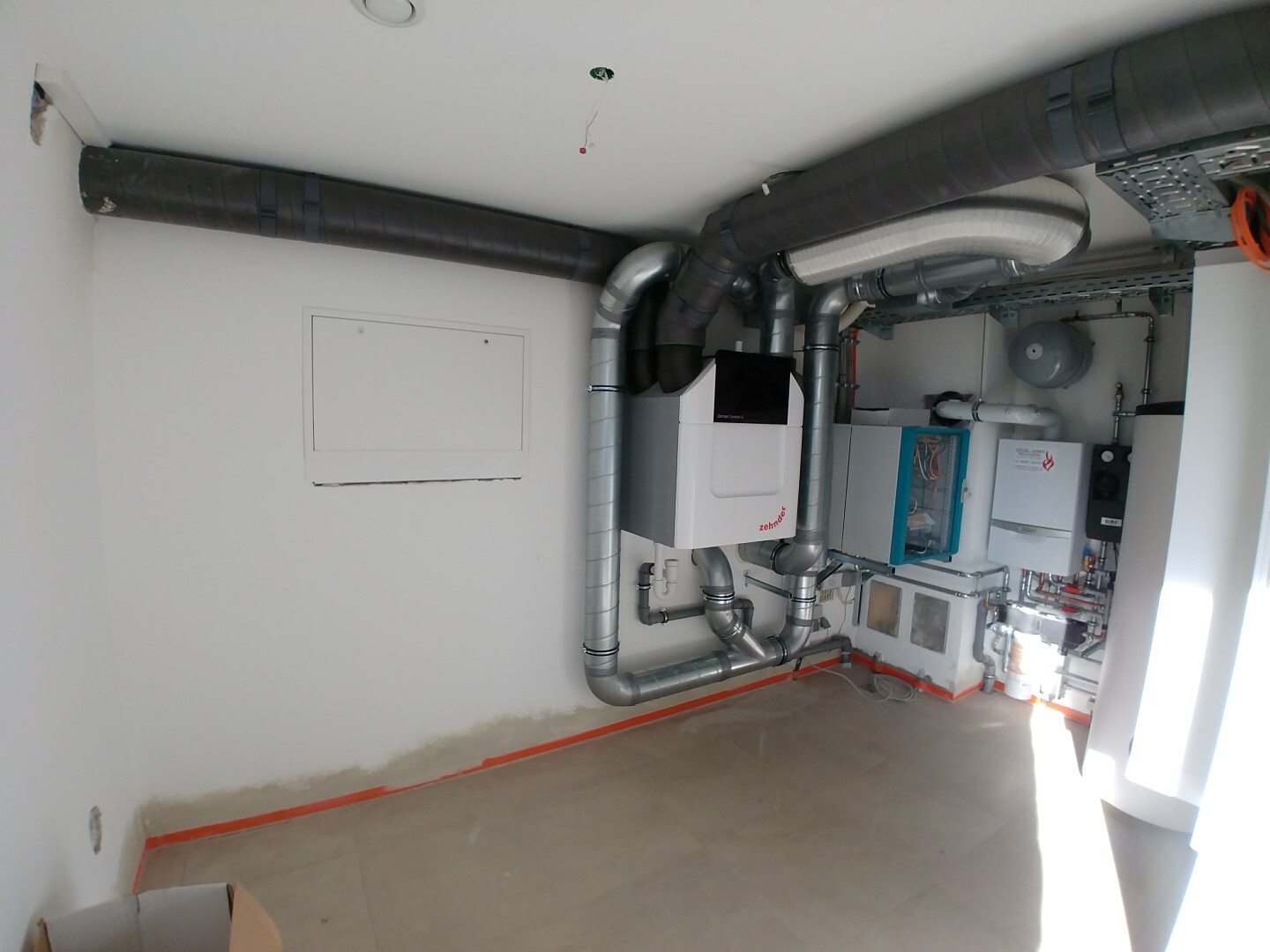 Utility room with heating and ventilation system, many galvanized pipes, and control cabinets.