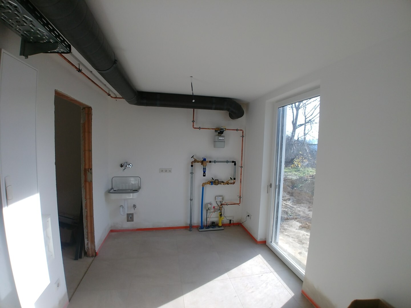 Sanitary room with visible pipes, sink, gas meter, and window to the outside.