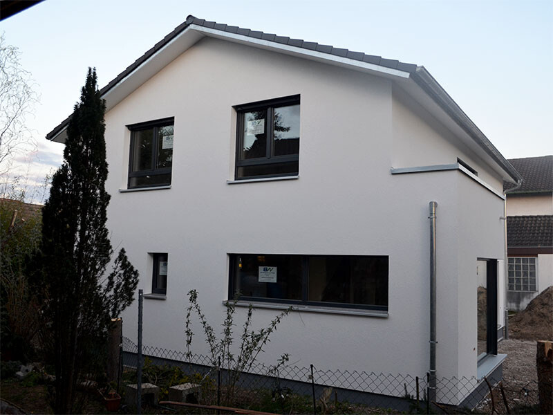 Modern white single-family house with large windows and garden fence.