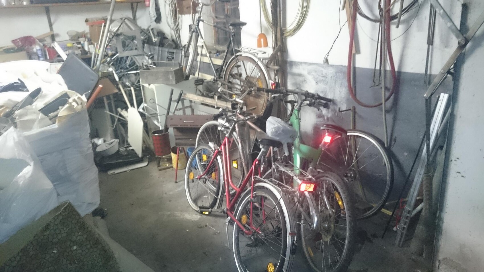 Chaotic garage with several bicycles, tools, and stored goods.