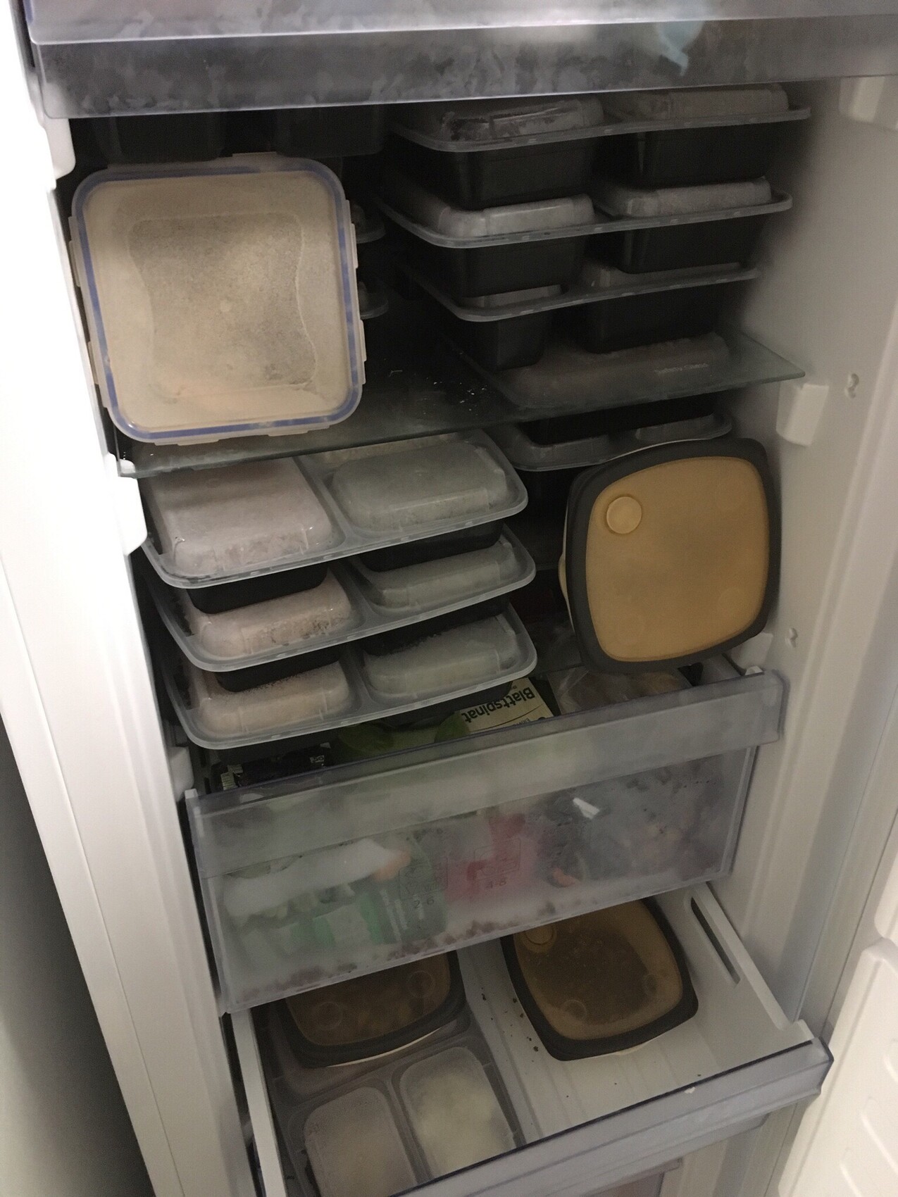 Open freezer with multiple drawer containers and storage boxes.
