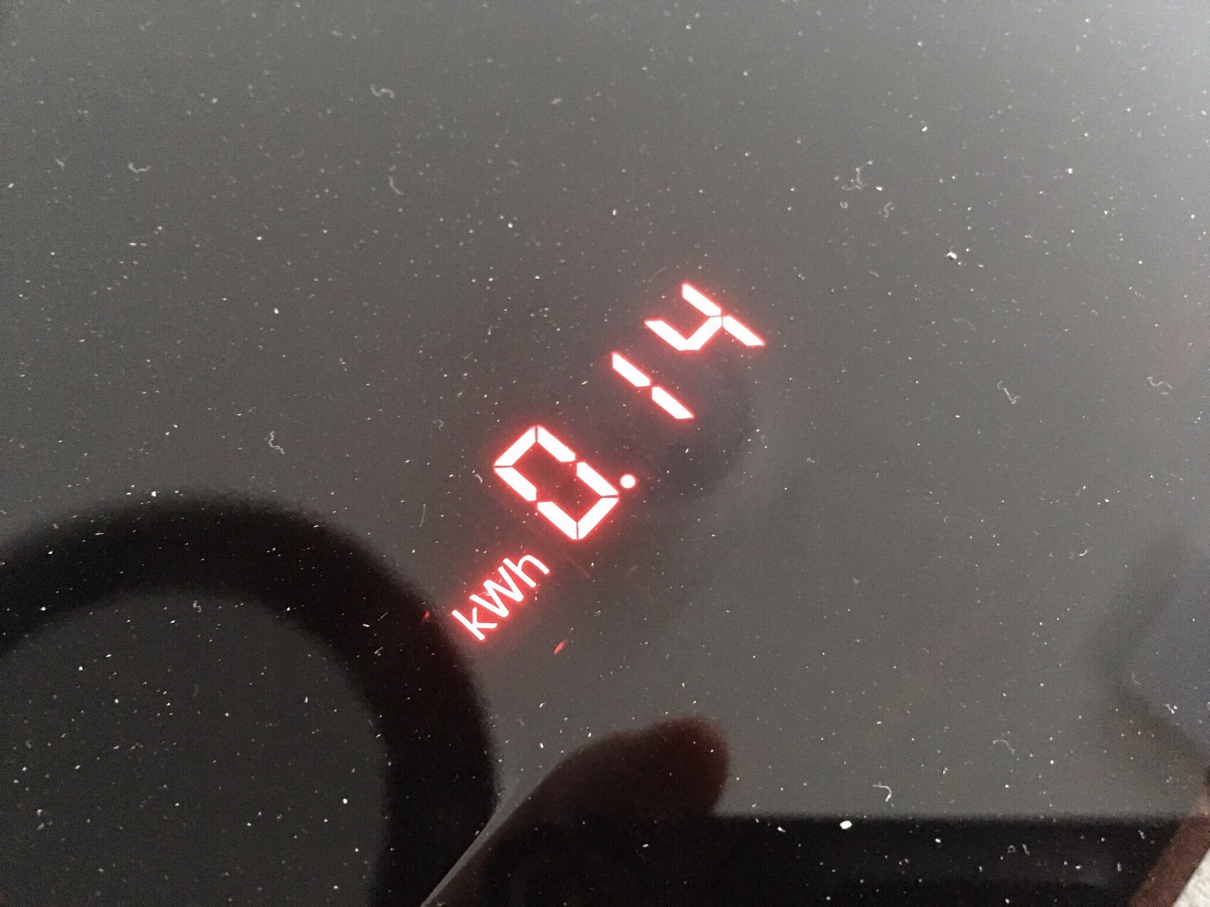 Red digital kWh display on black glass surface