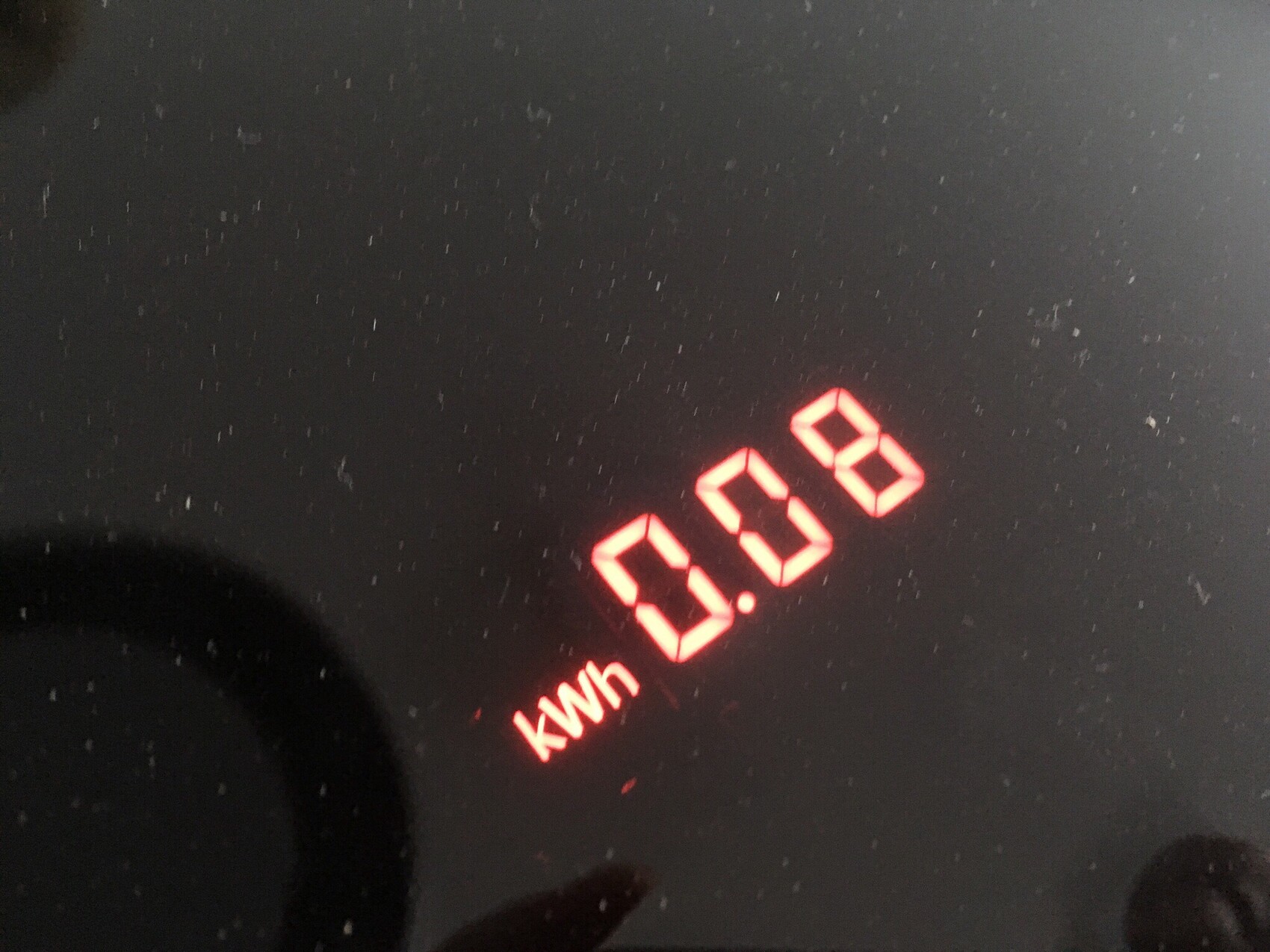 Red digital kWh display lights up on dark surface.