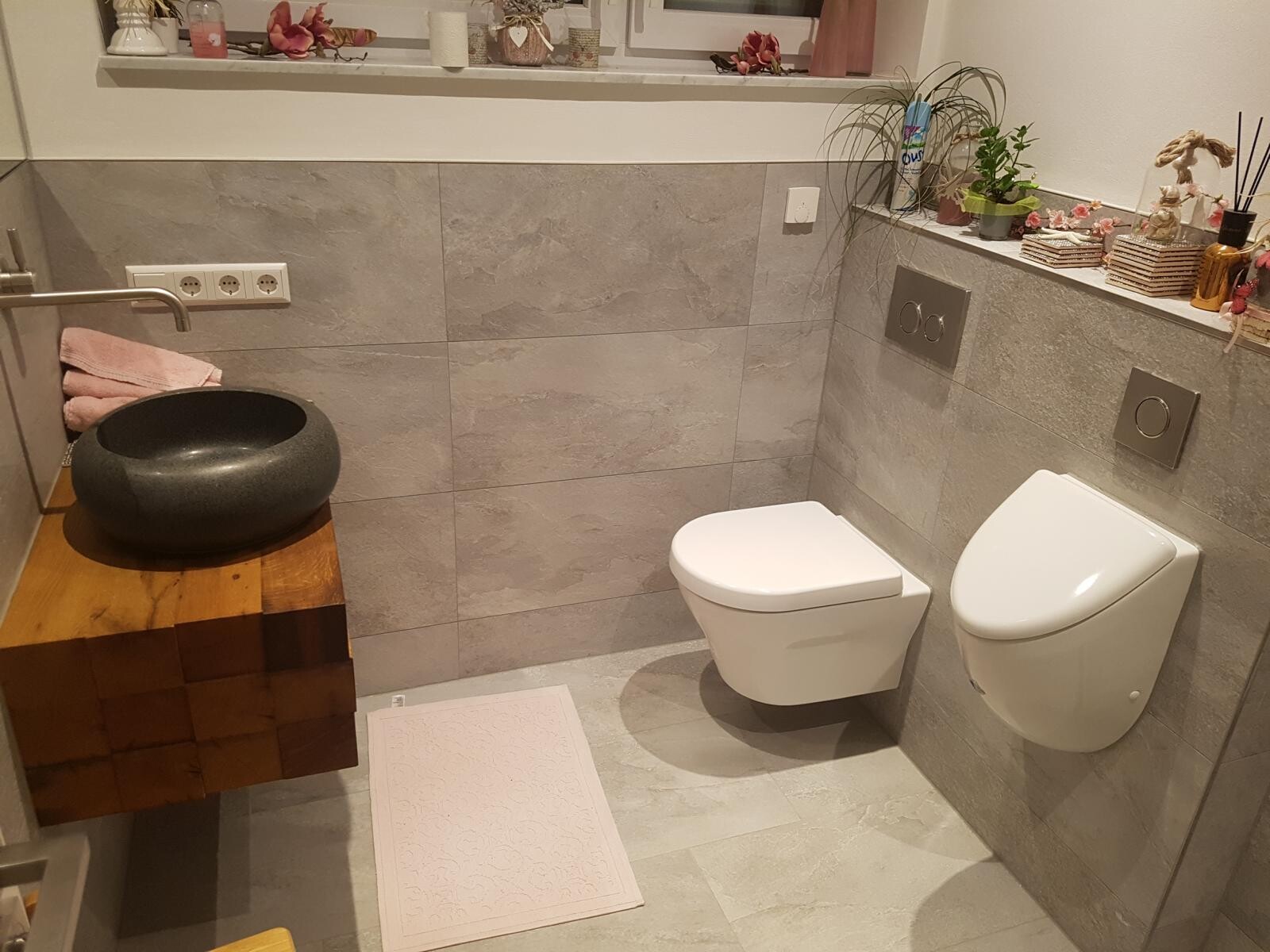 Modern bathroom with wall-mounted toilet, black stone washbasin, and wooden base.