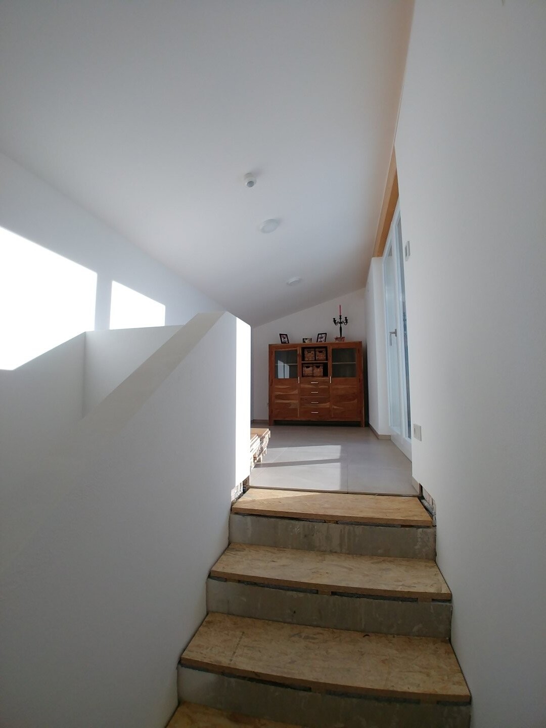 Modern bright staircase in hallway with white walls and wooden steps