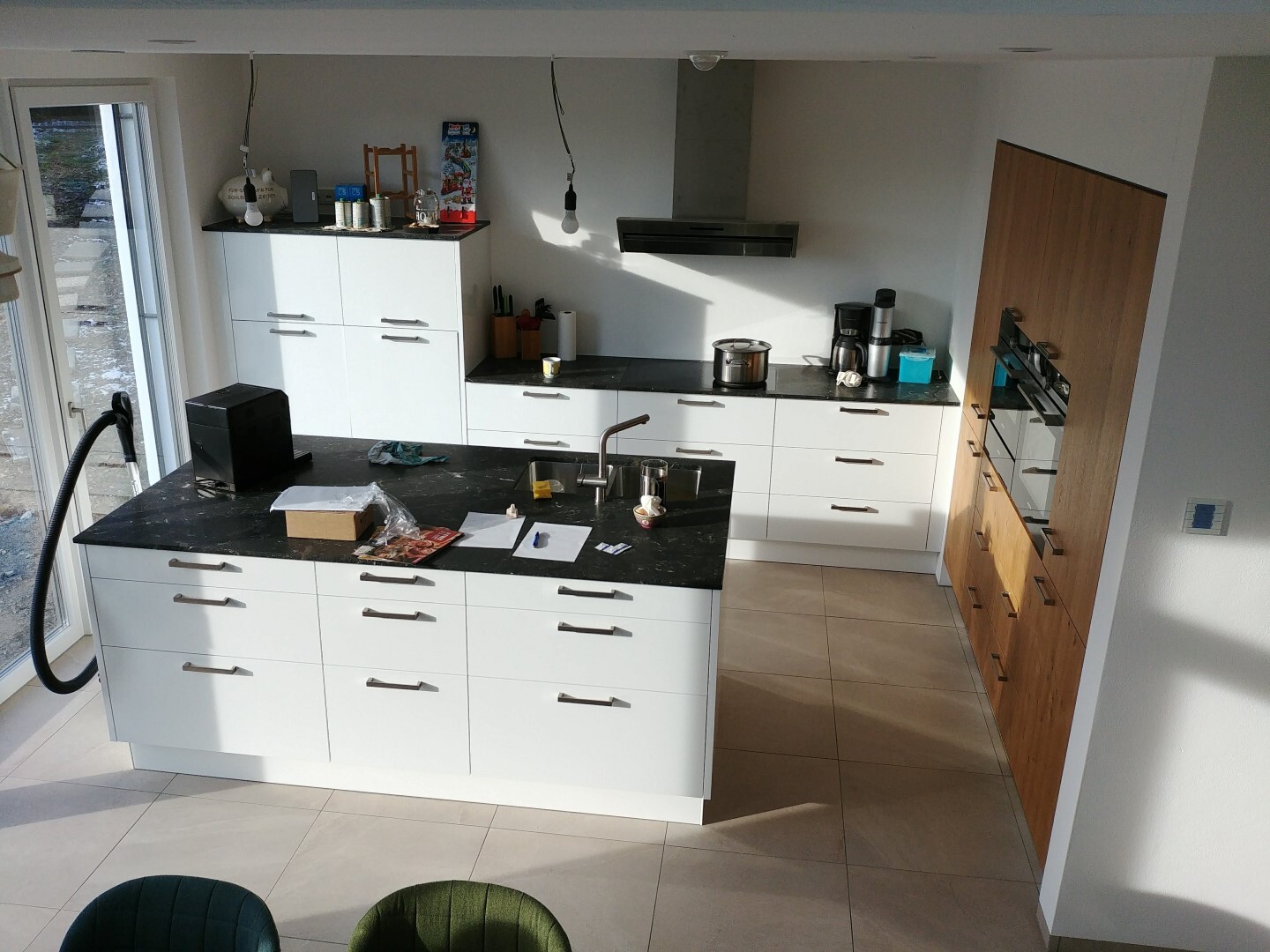 Modern kitchen with white fronts, dark countertop, cooking island, and wood fronts.