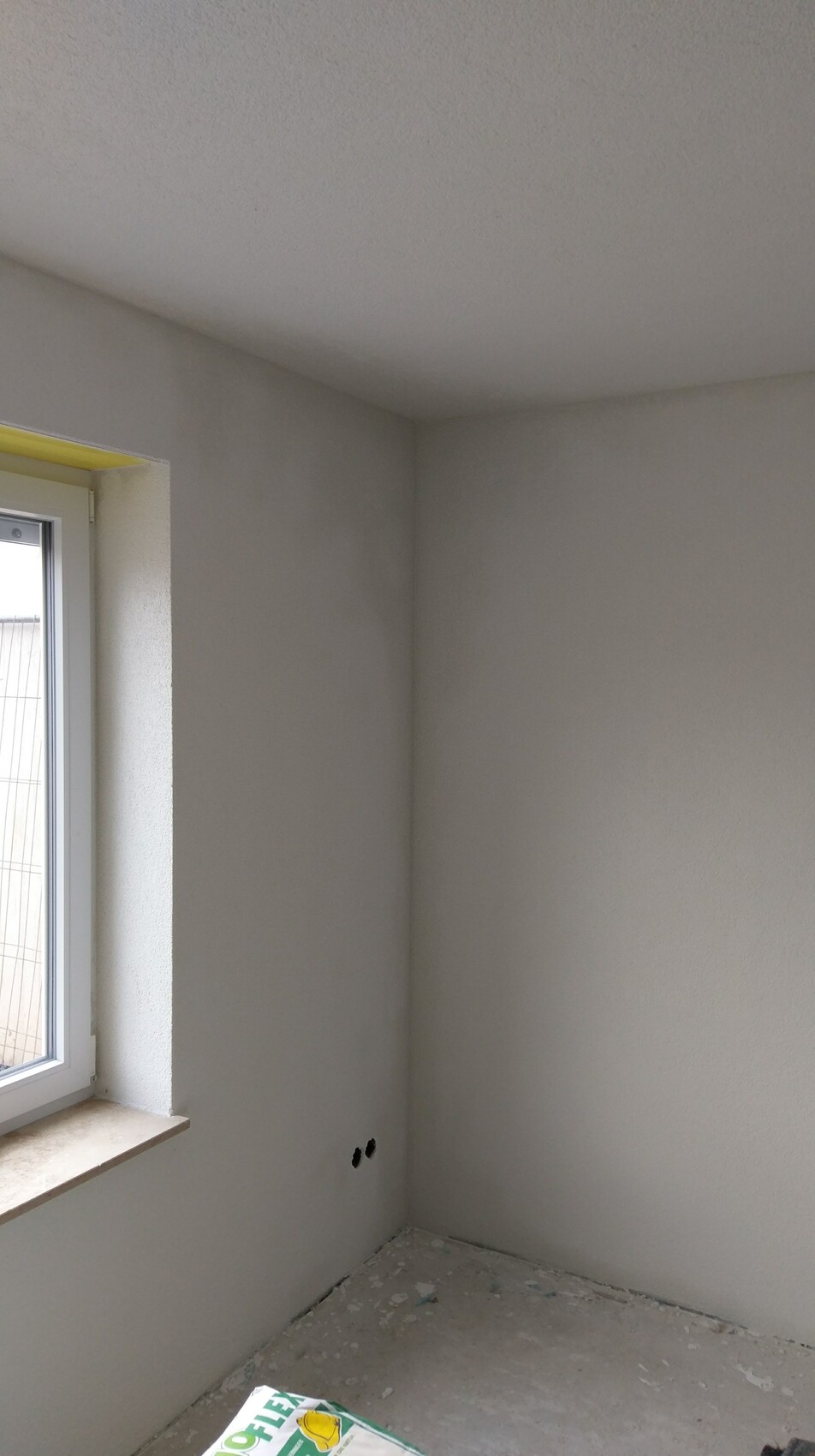Interior under construction: plastered walls, window front, floor with construction debris