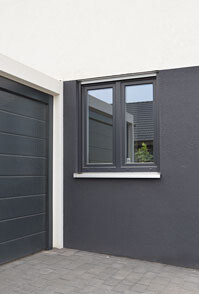 Exterior view of a modern house with dark facade, garage door on the left, and small window