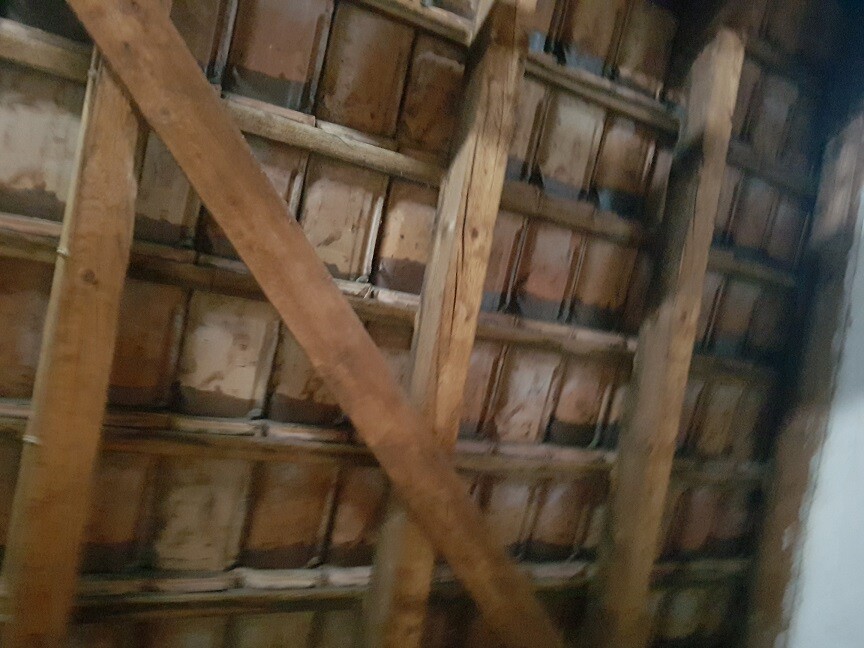 Attic with wooden beams, diagonal brace, and wooden walls.