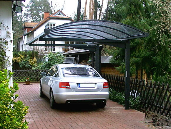 Silver car parked under a modern carport canopy on a paved driveway.