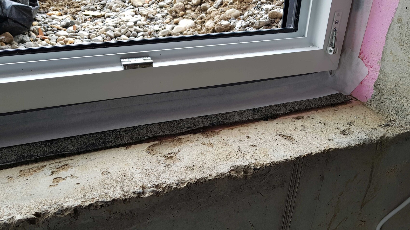 Window frame in the shell construction with concrete window sill and pink insulation on the masonry