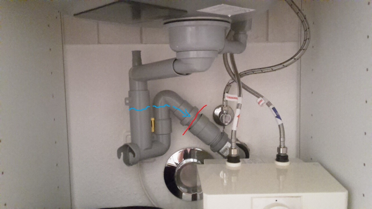 Under the sink: trap, pipes, and two water connections inside the cabinet.