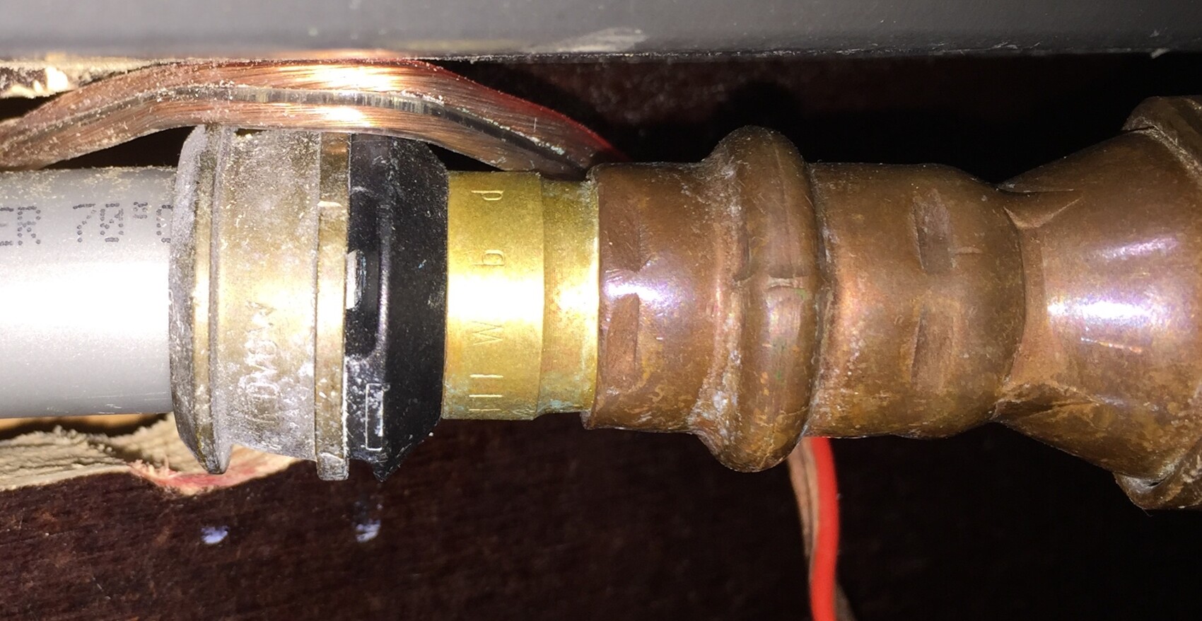 Close-up of a pipe connection with copper pipes and brass fittings under the sink