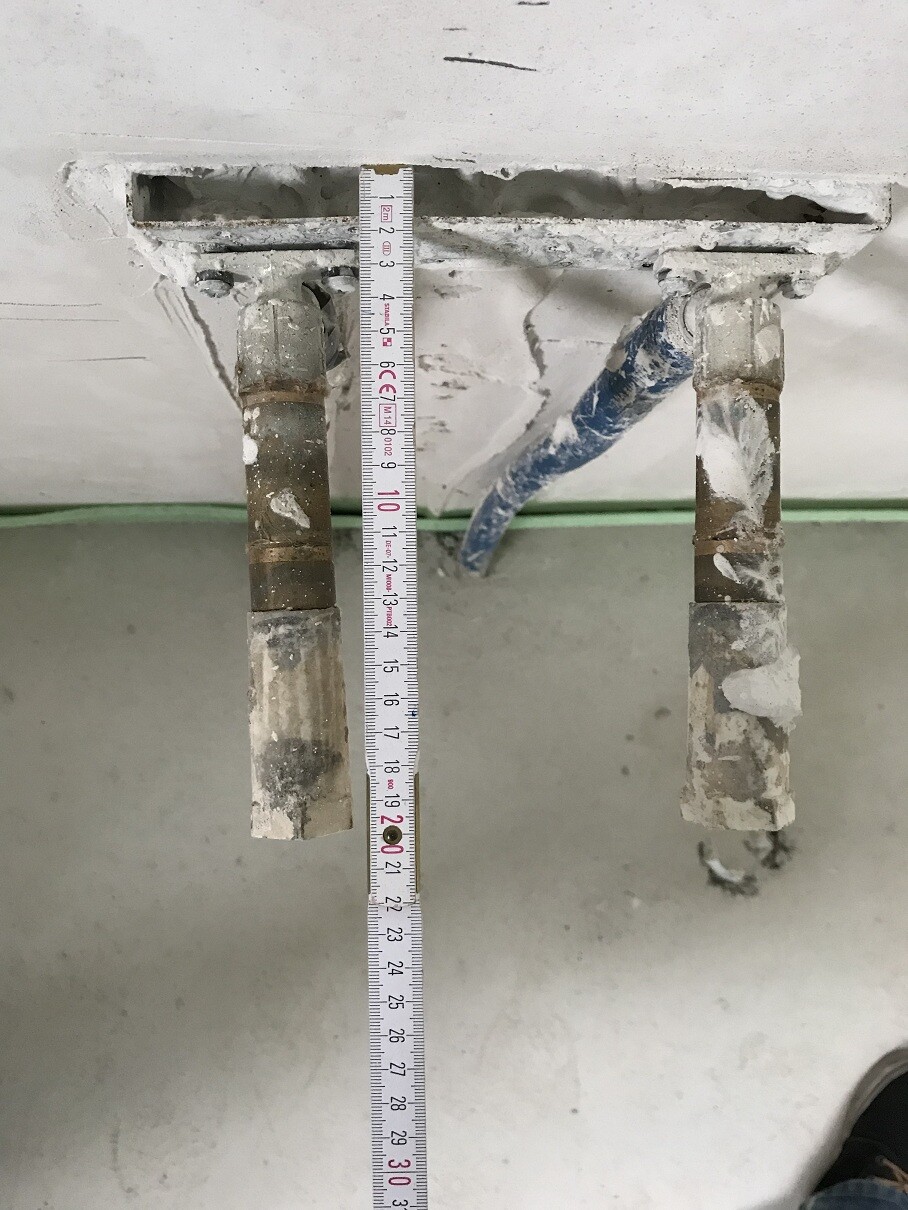 Two pipes in a wall, measuring tape used to measure the pipe installation.