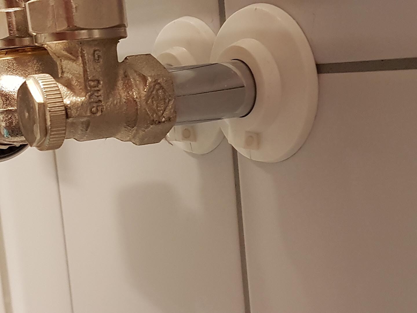 Close-up of a wall connection with shut-off valve on a pipe in a plumbing installation