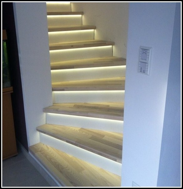 Moderne Holztreppe mit LED-Beleuchtung unter jeder Stufe in weißem Innenraum.